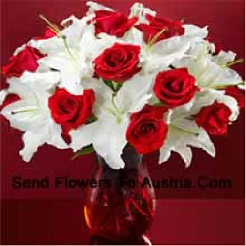 Roses rouges et lis blancs avec quelques fougères dans un vase en verre