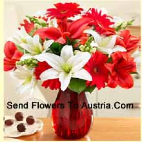 Gerberas rouges, lys blancs, lys rouges et autres fleurs assorties disposées magnifiquement dans un vase en verre